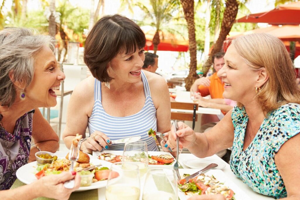 Three women are eating at a table outside.