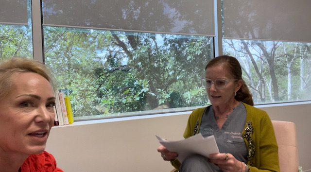 Two woman sitting opposite to each other and one reading a document.