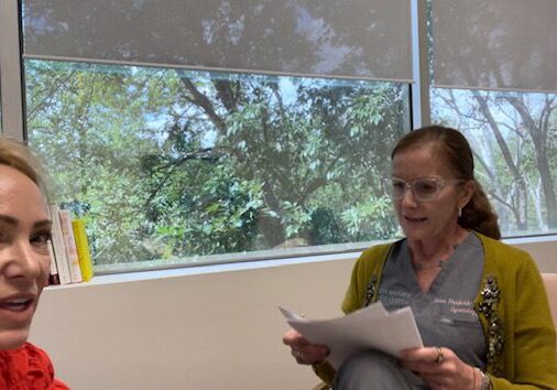 Two woman sitting opposite to each other and one reading a document.