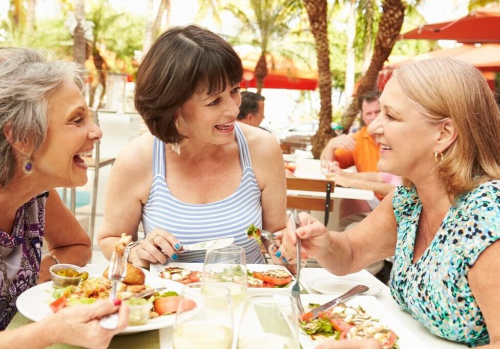 Three women are eating at a table outside.