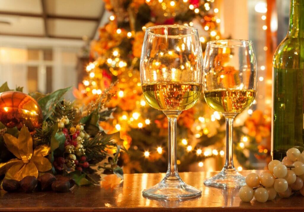 A beautiful shot of two glasses of alcohol on the counter with a christmas tree in the back